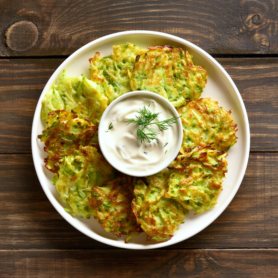 Zucchinipuffer mit Joghurtdip auf einem Teller